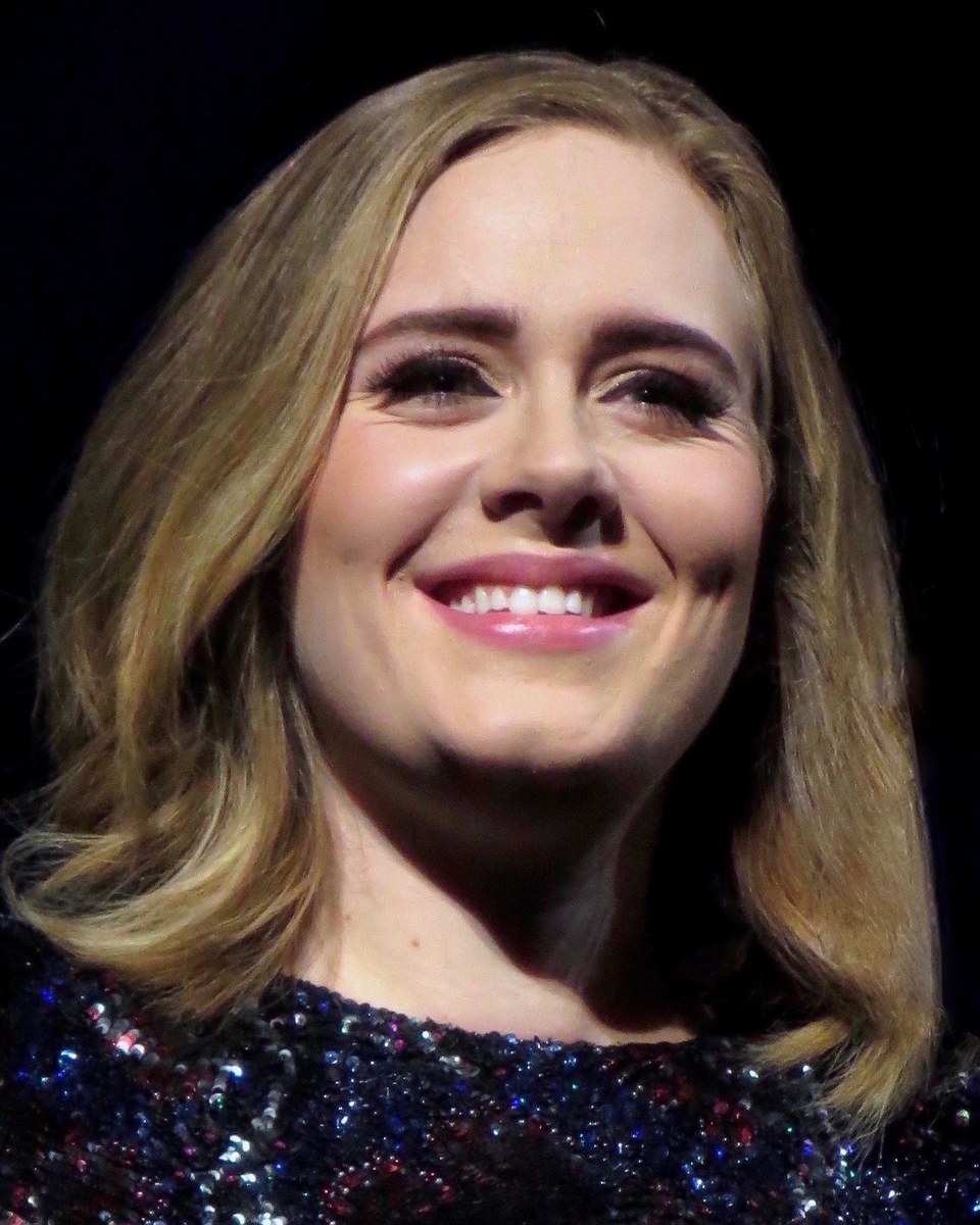 Adele smiling on stage in a sequined top in 2016