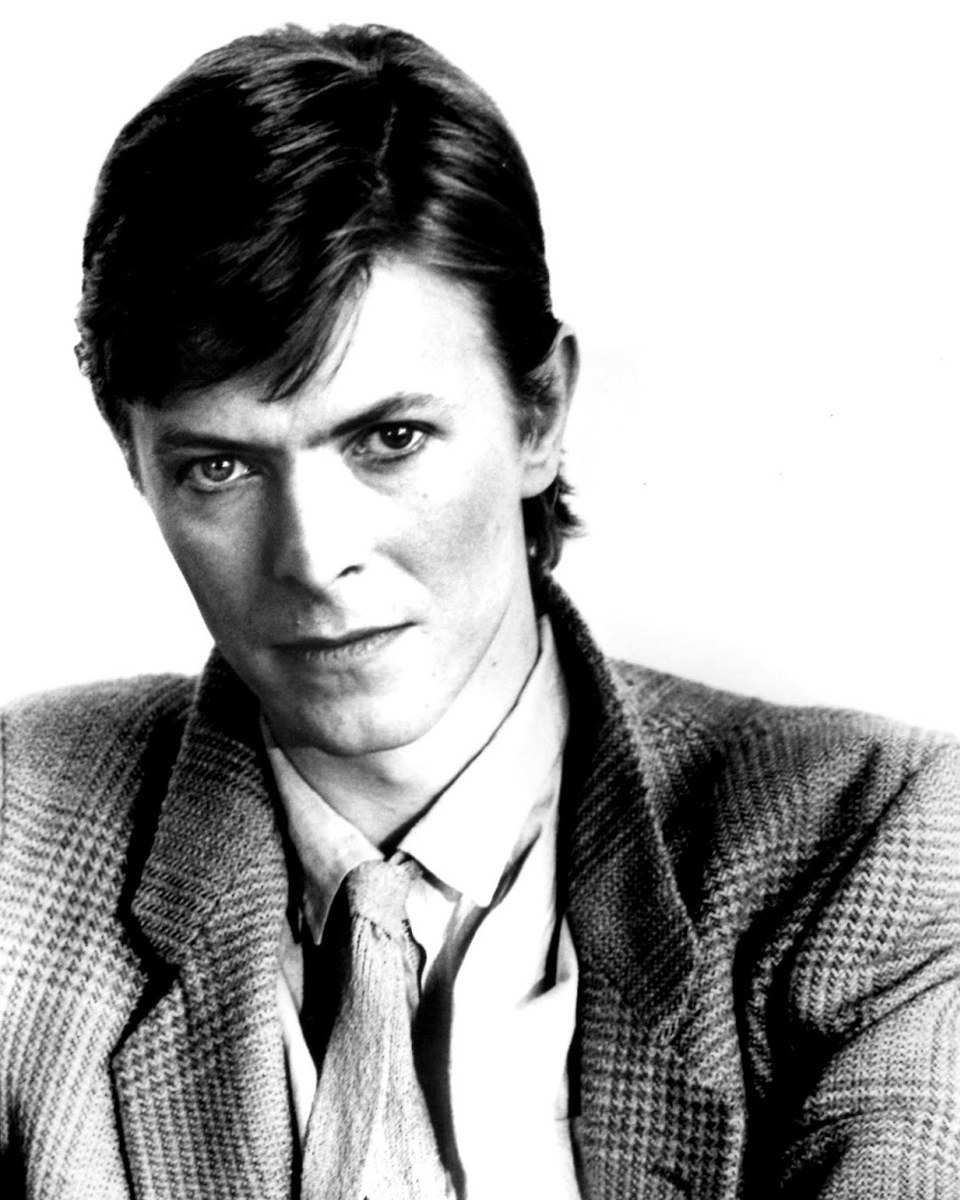 David Bowie in a check jacket and knitted tie, black-and-white publicity photo from 1979