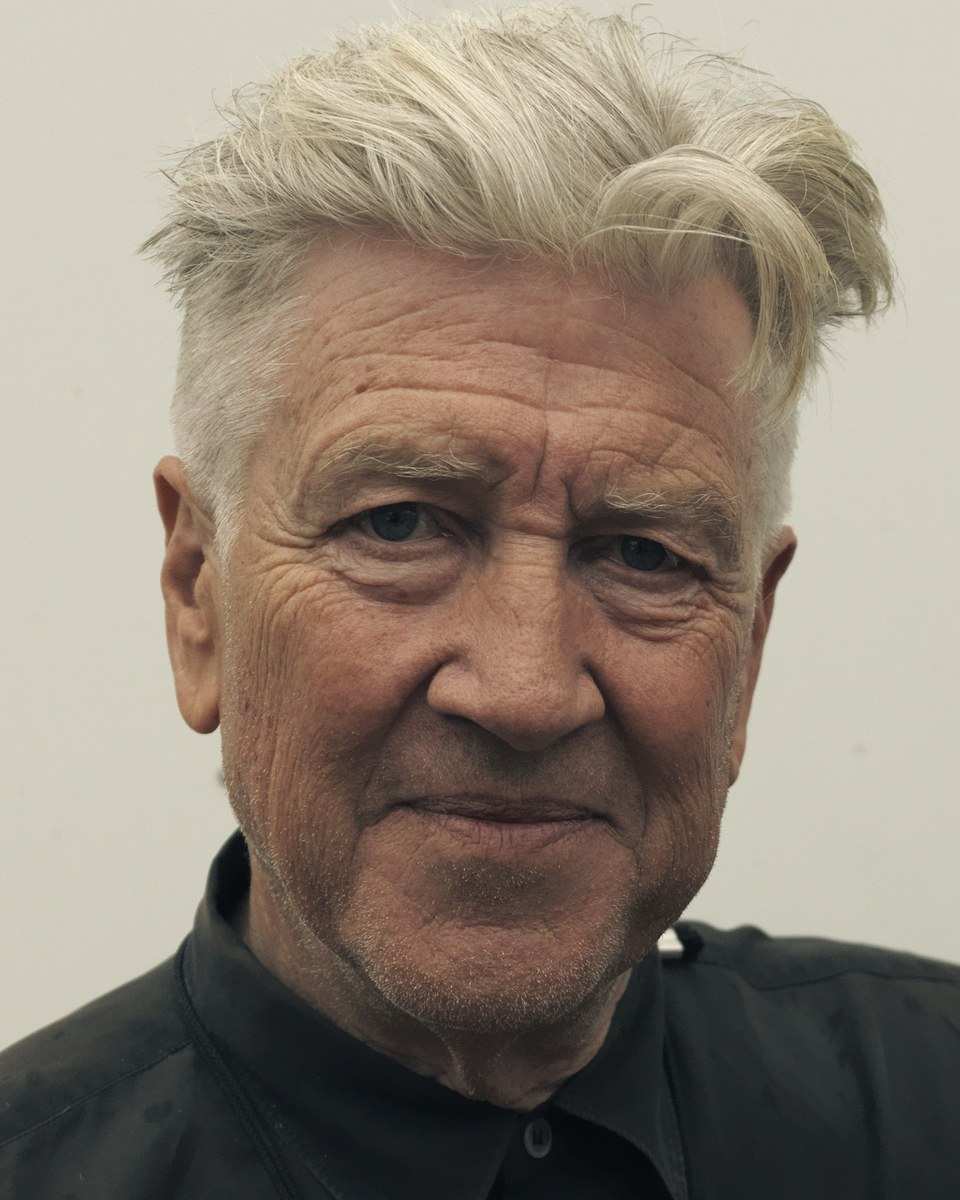 David Lynch with swept-up white hair in a black shirt in 2016