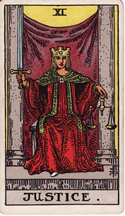 The Justice card of the Rider–Waite–Smith deck: a crowned figure in a red robe and green cloak sits between two gray pillars before a purple curtain, holding an upright sword in one hand and golden scales in the other