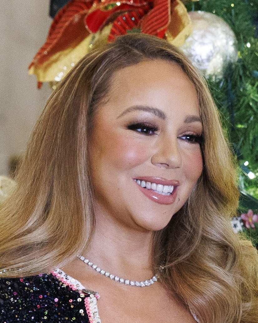 Mariah Carey smiling in front of a Christmas tree at the Library of Congress in 2023