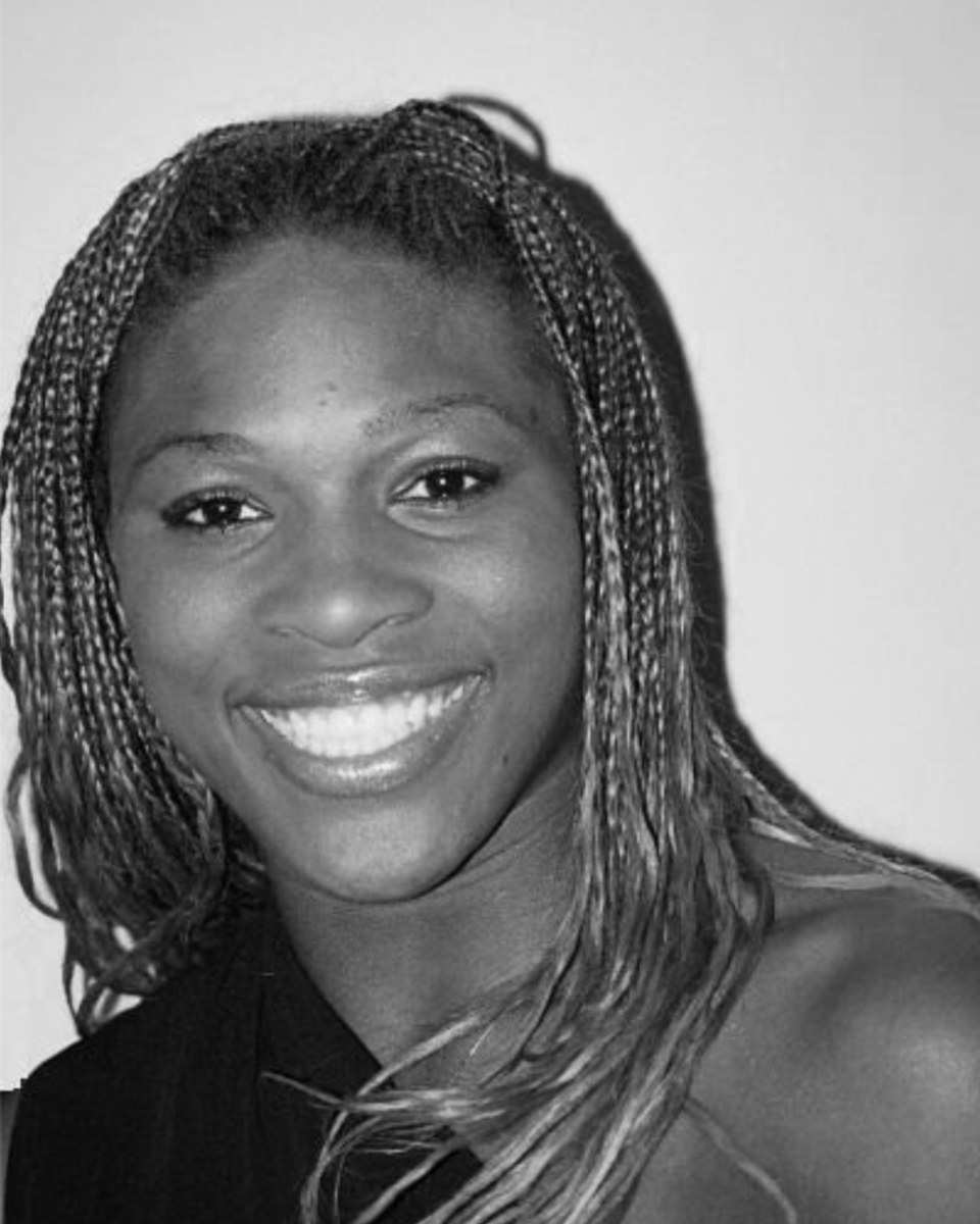 Serena Williams smiling in a black-and-white portrait, with long braids