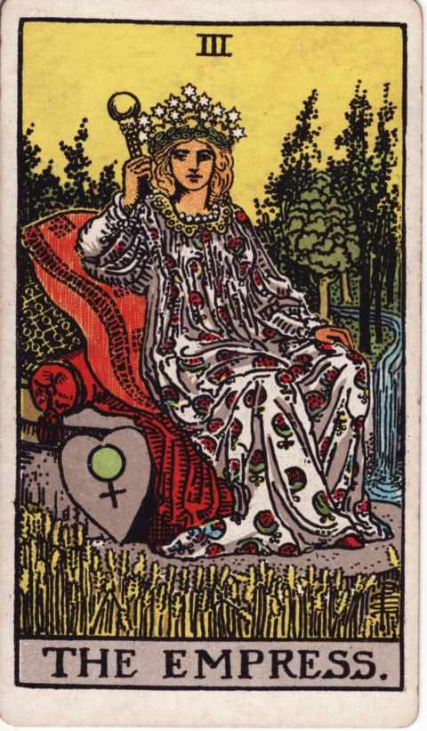 The Empress card of the Rider–Waite–Smith deck: a woman crowned with twelve stars sits on red cushions holding a scepter, a heart-shaped shield with the Venus symbol beside her, ripe wheat in front and a waterfall among cypress trees behind