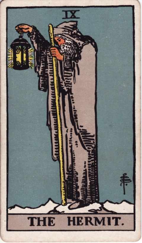 The Hermit card of the Rider–Waite–Smith deck: an old bearded man in a gray hooded cloak stands on a snowy peak, holding up a lantern with a six-pointed star inside and leaning on a tall staff