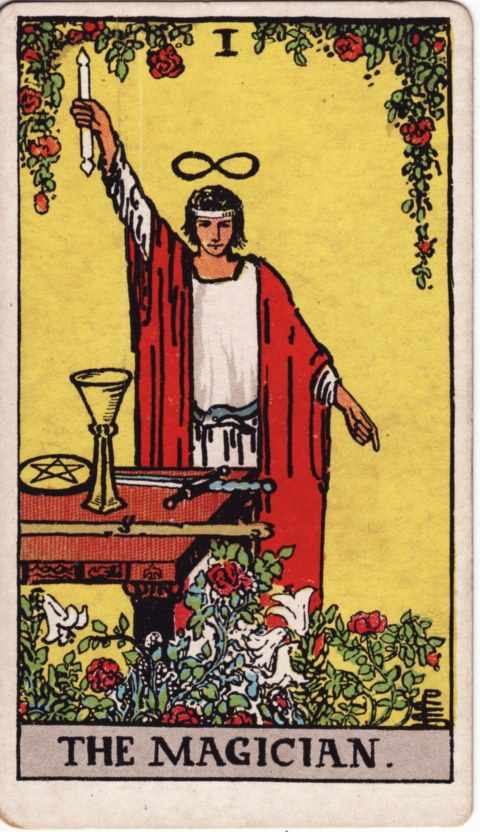 The Magician card of the Rider–Waite–Smith deck: a man in a red robe raises a white wand and points to the ground, an infinity sign above his head, a cup, pentacle, sword and wand on the table, roses and lilies below